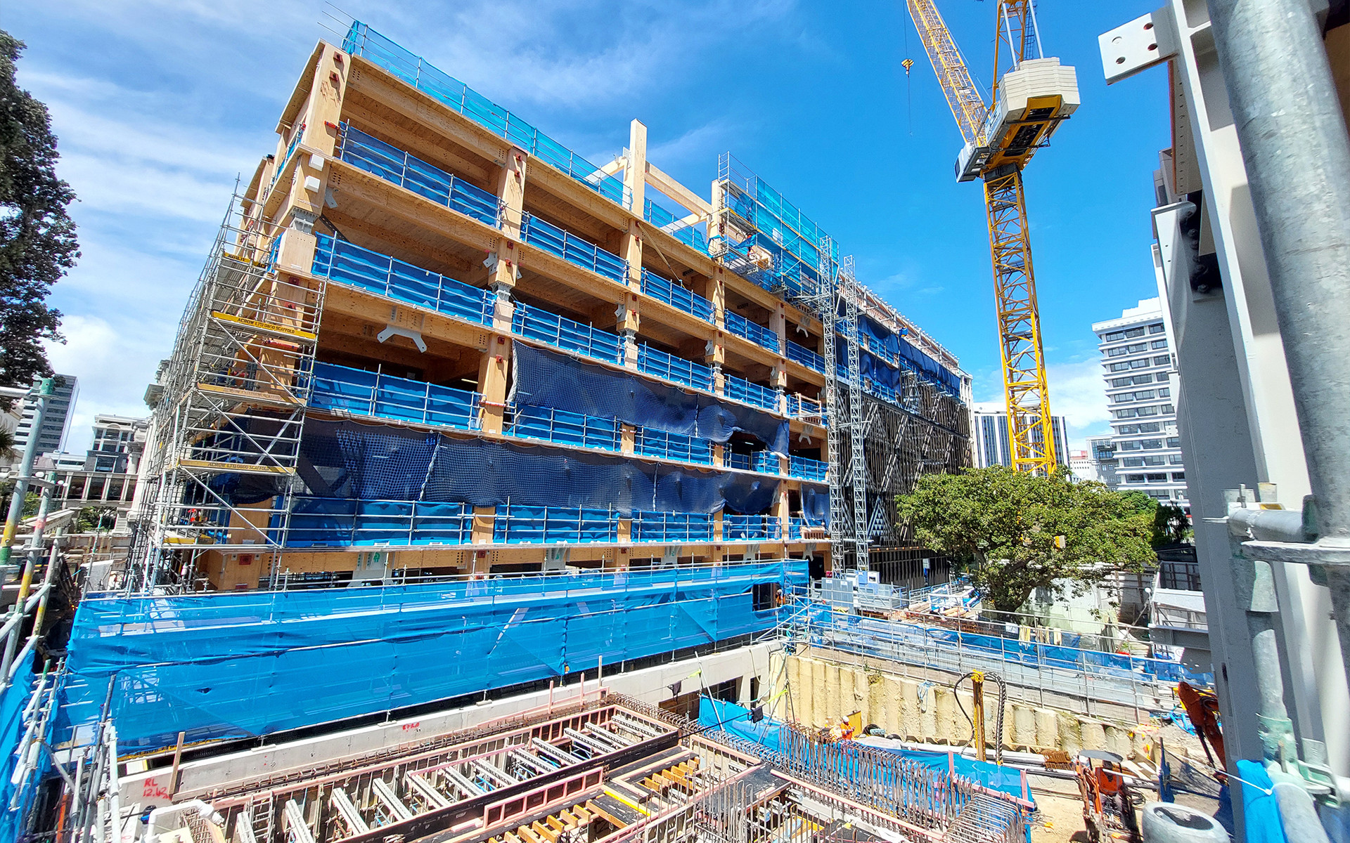 Mass timber building under construction with crane and foundation works, highlighting low-carbon construction and design for assembly.  